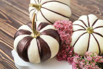 Composition with Halloween pumpkins and flowers on wooden table, closeup