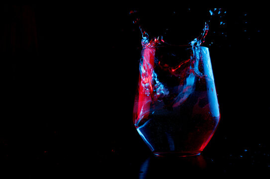 Water highlighted in blue and red splashing into a glass