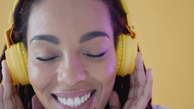 Beautiful jamaican woman with dreadlocks portrait and face expressions set in studio. Latin american woman dancing and making party over a yellow background