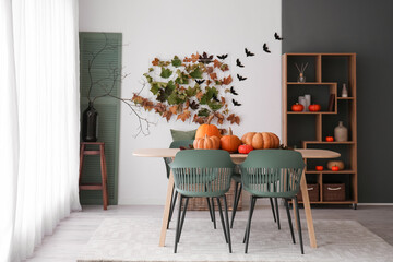 Interior of modern kitchen with fresh pumpkins, dining table and shelving unit