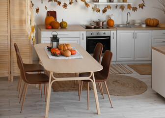 Interior of light kitchen decorated for Halloween with dining table and counters