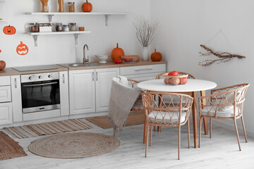 Interior of light kitchen decorated for Halloween with dining table and counters