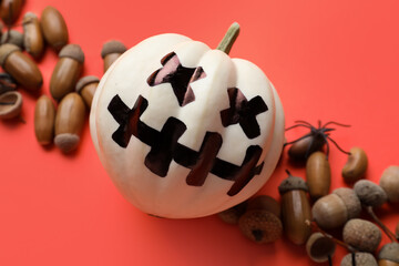 Composition with Halloween pumpkin and acorns on color background, closeup