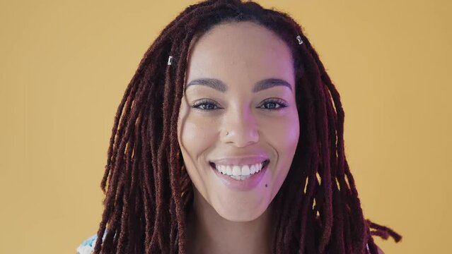 Beautiful jamaican woman with dreadlocks portrait and face expressions set in studio. Latin american woman dancing and making party over a yellow background