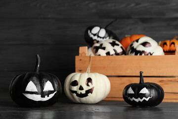 Box with different Halloween pumpkins on dark wooden background