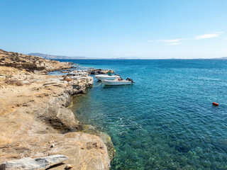 Greece Tinos island, Cyclades. Moored yachts at seaside rocky land in vast Aegean ripple sea.