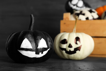 Halloween pumpkins with drawn faces on dark wooden background