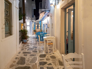 Greek outdoors tavern restaurant at Tinos island, Chora town Cyclades Greece. Illuminated lampposts.