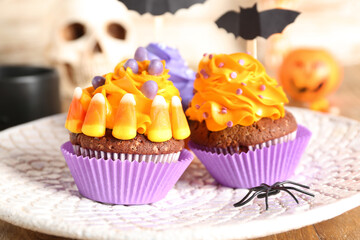 Plate with tasty Halloween cupcakes on wooden table, closeup