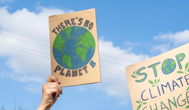 Protesters holding signs with slogans There's no planet B and Stop Climate Change. People with placards at protest rally demonstration, strike against global warming.