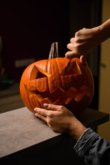 female hand with knife accurate cuts scary face on pumpkin . Decor for halloween