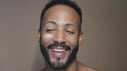 Handsome man taking care of his skin with beauty natural products and treatments. Latin american male posing on a background in studio. Beauty lighting set up and close up angles