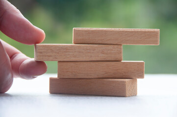 Hand pulling one wooden block with customizable space for text or ideas. Copy space