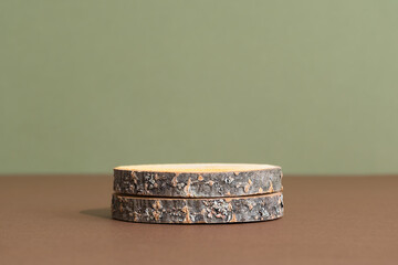 Wooden slice podium on a brown table on a green background. Premium empty scene for product promotion, beauty, natural eco cosmetic. Showcase, display case.
