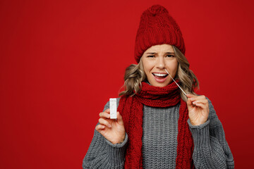 Young sad displeased woman wear grey sweater scarf hat do coronavirus covid-19 test isolated on...