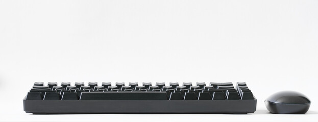Portable computer keyboard equipped with mechanical switches and a black computer mouse on a white...