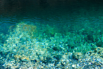 Texture of emerald clear water and natural stones. Natural background. Blue Lake.