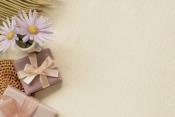 Purple gift boxes and flower on beige fabric background. flat lay, top view, copy space