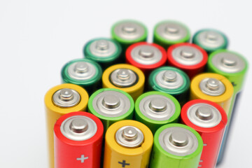 Different colours of batteries on white background. Close up of positive ends batteries, selective focus. Used battery for recycling. Hazardous garbage concept