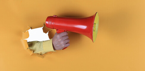 megaphone in hand in yellow paper hole