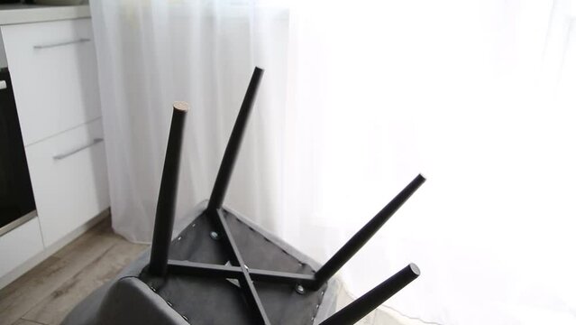 A man glues protective pads on the legs of a chair. Protection against floor scratches and noise