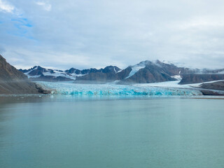 Obraz premium Panorama view of the 14th of July Glacier or the Fjortende Julibreen. Is a beautiful glacier found in northwestern Spitsbergen. Floating Pack Ice in the arctic ocean. Dramatic sky with place for text.