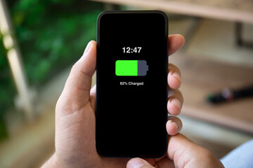 man hands holding phone with charged battery on screen