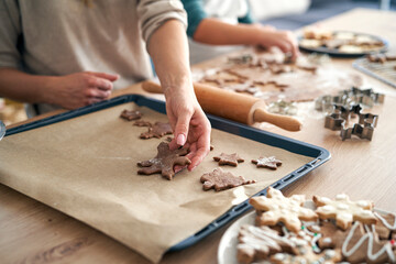 Fototapeta na wymiar Detail of caucasian woman putting raw gingerbread cookies on baking tray