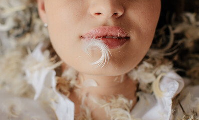 Anonymous woman with feather on her lips