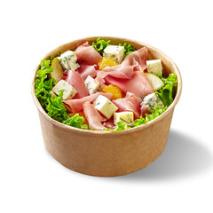 Paper bowl of salad with lettuce, blue cheese, prosciutto, pear, orange and mustard dressing isolated on white