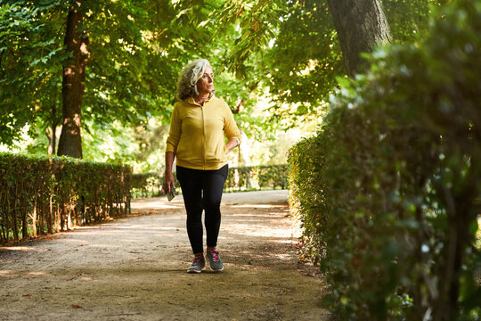 Aged sportswoman walking in park