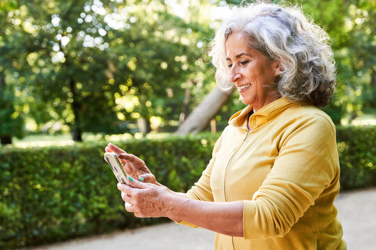 Glad senior sportswoman reading message on cellphone