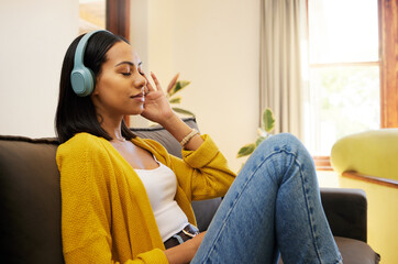 Woman, music and relax with headphones on living room sofa enjoying calm relaxation at home. Young...
