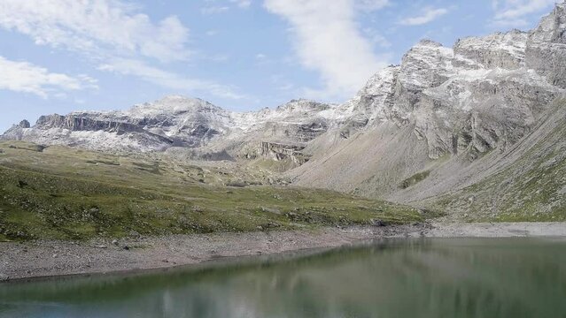 Mountain lake with green water and light blue sky. Reflection in the water. Beautiful spring landscape with mountains, and lake. Aerial View. Drone shot over a beautiful mountain lake