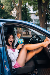 Fototapeta na wymiar Young woman sitting in a car and holding a globe