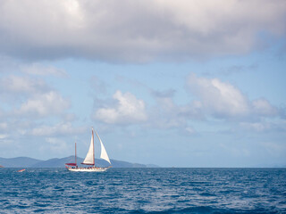 Distant sailboat against blue sky with white clouds