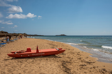 Beautiful beach with sand, turquoise and green water is a red patino in the foreground in Portopalo di Capo Passero