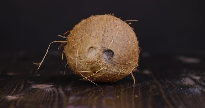 A whole coconut on a black background on a wooden board, a whole coconut with a shell