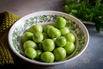 Green tomatoes in a plate on a table with a knitted napkin, rustic style, horizontal