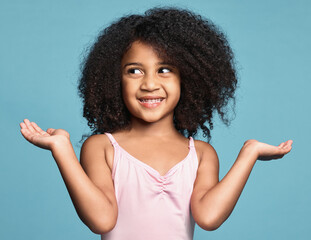 Girl, hands and smile with confused, question and guess against studio background. Kid, model and confusion do sign for doubt against blue backdrop with shrug, afro and natural hair on surprise child