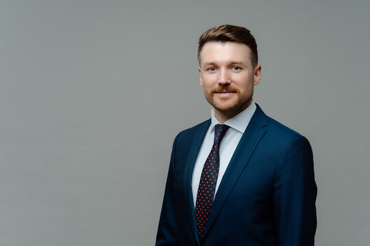 Confident Male CEO In Formal Outfit Has Good Business Reputation Looks Smart At Work Isolated Over Grey Studio Backgrounf With Copy Space For Your Promotion. Charismatic Employer Poses Indoor