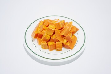 Sliced ​​ripe papaya fruit on a plate, ready to eat, view from above, white background.