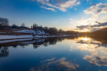 Winter landscape with river and trees at sunset.