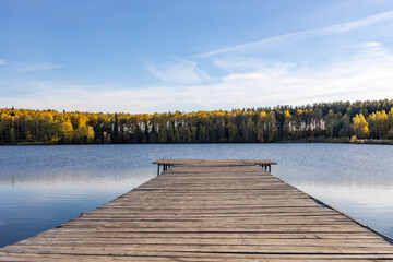 Obraz premium Wooden deck near the water. Sunny autumn day near the pond.