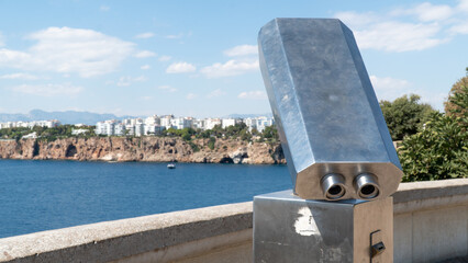 Stationary viewing binoculars in the park with a view of the city and the rocks