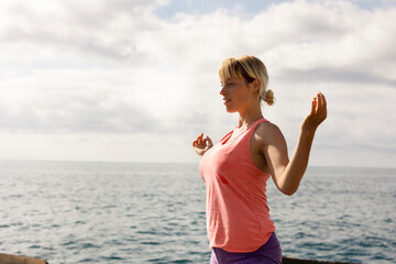 Beautiful young woman practising yoga outside. Fit woman doing stretching exercises at the beach