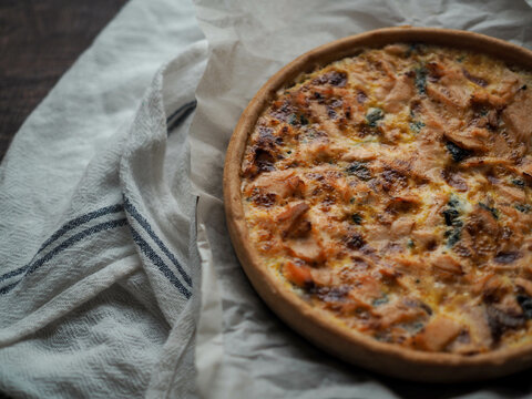 Home made salmon Quiche on a wood table with beautiful light for background