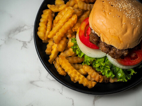 Homemade pork hamburger with fresh lettuce, tomato, fried egg and fresh onion on a white table