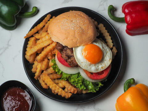 Homemade pork hamburger with fresh lettuce, tomato, fried egg and fresh onion on a white table