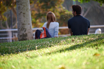 Relaxed and calm couple, sitting in a park with grass, having a conversation.